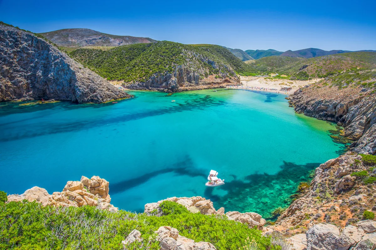Cala Domestica a Buggerru vista dall'alto con mare turchese , scogliere e spiaggia sabbiosa