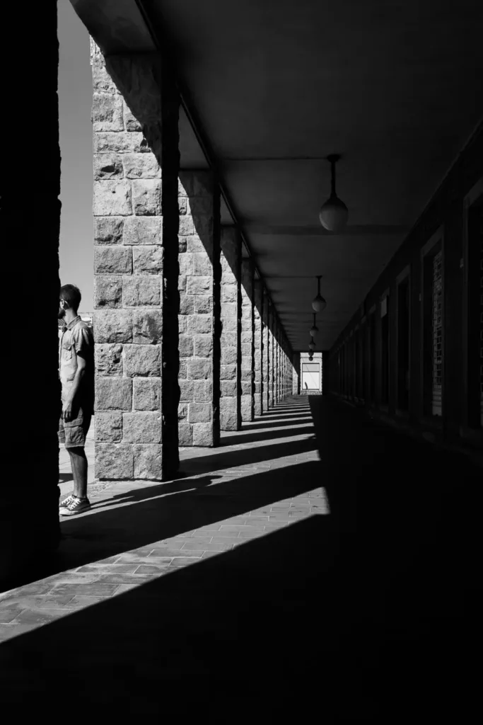 Luce e ombra lungo un portico di Cortoghiana, in una fotografia in bianco e nero.