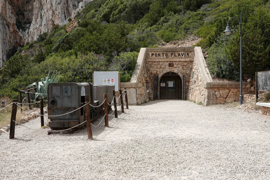 Ingresso della galleria di Porto Flavia, con un vagoncino esposto all’esterno.