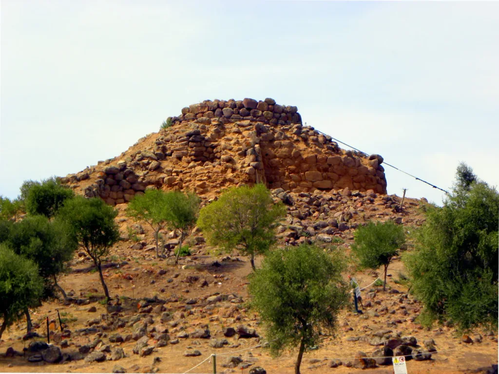 I resti in pietra del Nuraghe Sirai, con vegetazione lungo il pendio.