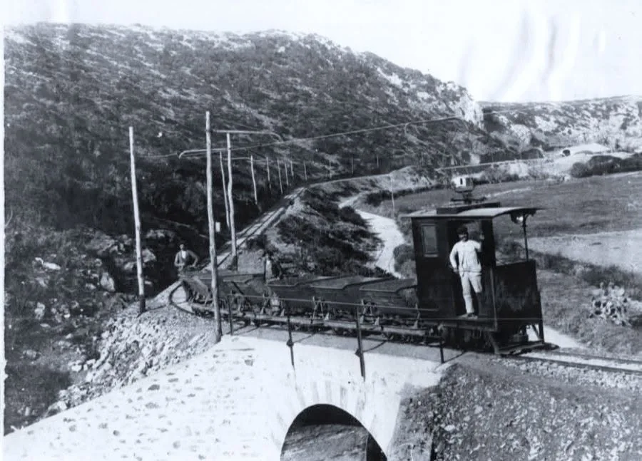Piccola locomotiva elettrica con carri su un ponte in muratura