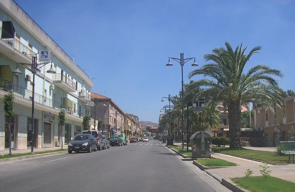 Edifici di più piani e palme lungo viale Gramsci a Carbonia