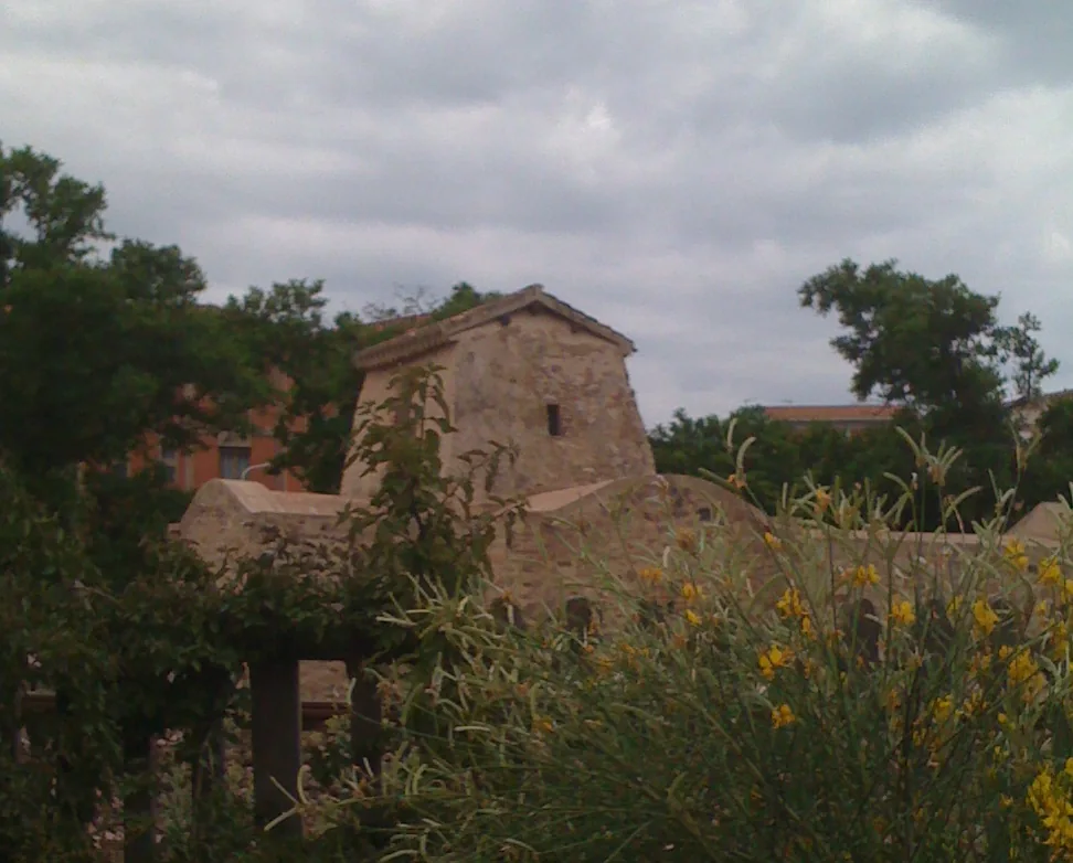 Volumi in pietra di San Salvatore fra vegetazione ed edifici a Iglesias