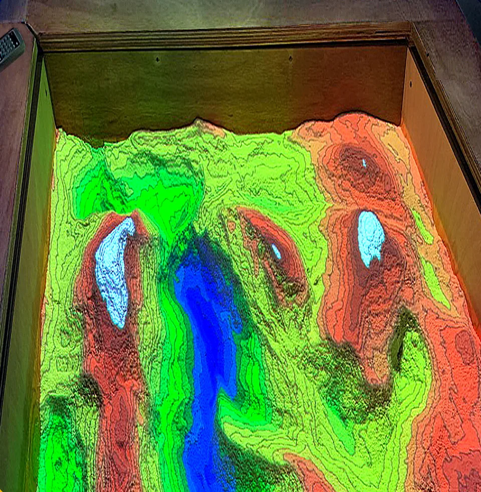 La sandbox del GeoPunto: colori e curve di livello proiettati su una superficie modellabile, 2024.