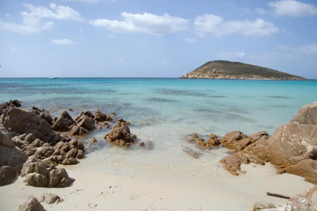 L’isola di Tuerredda vista dalla riva, con rocce e sabbia in primo piano