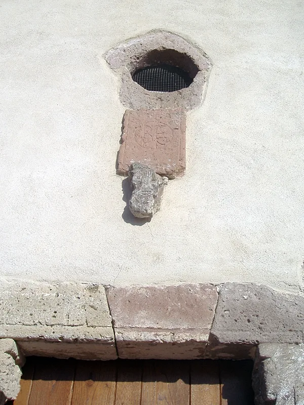 Apertura superiore, lastra incisa ed elemento scolpito sulla facciata di Santa Marta